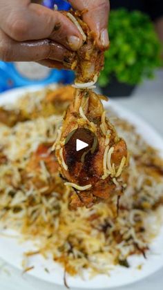 a person is holding up some food on a white plate with shredded noodles and meat