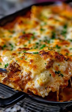 a cheesy casserole with meat and cheese is being held by a fork