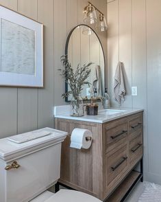 a white toilet sitting next to a wooden vanity in a bathroom under a large mirror