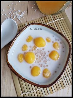 some eggs are sitting in a bowl on a bamboo mat next to a glass of orange juice