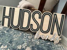 a wooden sign that says hudson banks sitting on top of a blue and white rug