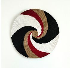 a black, white and red circular rug hanging on a wall in the shape of a spiral