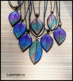 a bunch of necklaces that are hanging on a wall with some leaves attached to them