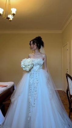 a woman in a white wedding dress standing next to a table with flowers on it