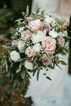 a bridal holding a bouquet of pink and white flowers in her hands with greenery