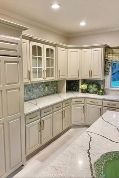 a large kitchen with white cabinets and marble counter tops, along with a green sink