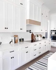 a kitchen with white cabinets and counter tops