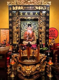 a man sitting on top of a golden throne in front of a painting and candles