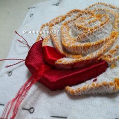 a close up of a piece of cloth with red ribbon on it and some scissors next to it