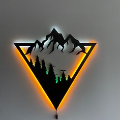 a triangle shaped clock with mountains and trees on the wall behind it is lit up by neon lights