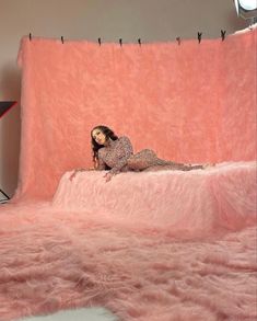 a woman laying on top of a pink bed covered in fake fur and posing for the camera