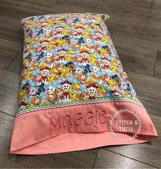 a child's bed with mickey mouse and friends sheets on it, sitting on the floor