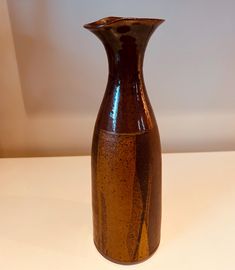 a brown vase sitting on top of a white table