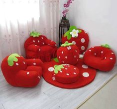 a group of red strawberry shaped chairs and ottomans on a white floor next to a window