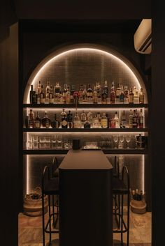 a dimly lit bar with lots of bottles and glasses on the shelves in front of it