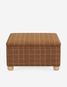 an upholstered footstool in brown plaid fabric