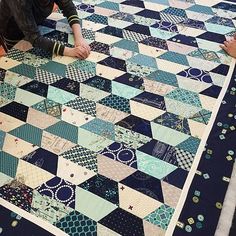 a woman is laying on the ground with her hand on a patchwork quilt that has been made