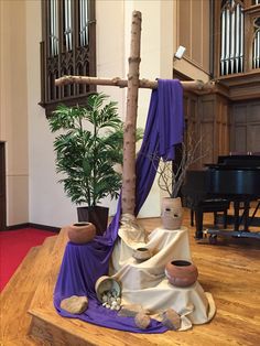 a cross made out of rocks and cloths in front of a tree with potted plants