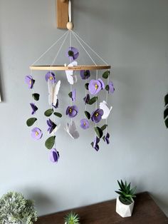 purple and white flowers are hanging from a wooden beam on the wall next to a succulent plant