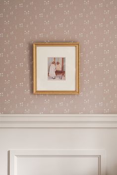 a framed photo hangs on the wall above a bed in a room with pink floral wallpaper