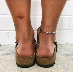 a woman's foot with a small sun tattoo on her left ankle and an anchor