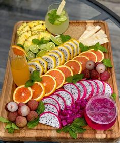 an assortment of fruits and vegetables are arranged on a wooden platter with juices