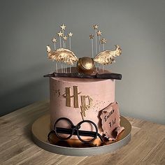 a birthday cake decorated with gold stars and scissors on a wooden table next to a pair of eyeglasses