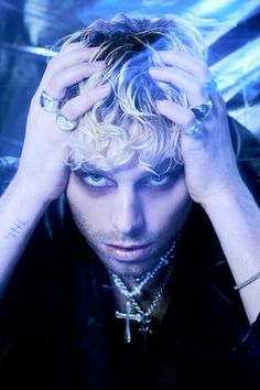 a man with blonde hair and piercings holding his hands to his head