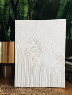 a white card sitting on top of a table next to a potted plant