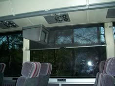 the inside of a bus with several seats and televisions on it's wall