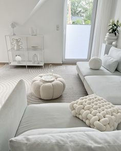 a living room with white couches and pillows on the floor in front of a window