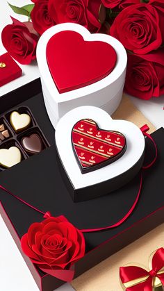 two heart shaped boxes filled with chocolates next to red roses and hearts on a table