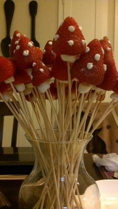 strawberries are arranged on sticks in a vase