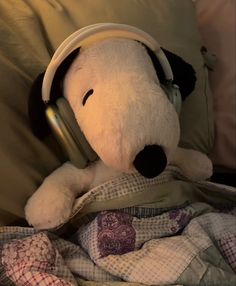 a stuffed dog wearing headphones on top of a bed