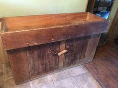 an old wooden cabinet with two doors on the top and bottom, in front of a tiled floor