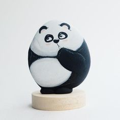 a black and white panda bear figurine sitting on top of a wooden base