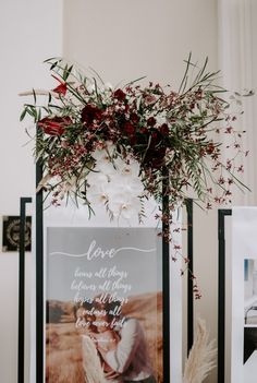 a photo frame with flowers and greenery on it next to a sign that says love