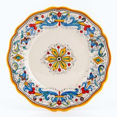 a white and yellow plate with an ornate design on the rim, against a white background