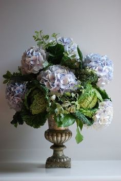 a vase filled with lots of purple and green flowers