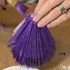 a person is using a purple brush to make something out of some sort of material