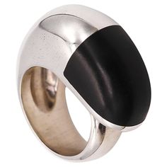 Geometric ring with wood designed by Monica Coscioni. Beautiful contemporary cocktail ring, created in the city of Orvieto Italy at the jewelry atelier of the designer Monica Coscioni. This modern geometric piece has been crafted in solid .925/.999 sterling silver, with very high polished finish and embellished with a carved piece of dark ebony wood. Weight: Combined of 33.90 grams (21.73 Dwt). Size: 9.5 sizeable. Measures: 33 mm x 14 mm (1.30 x 0.55 inches). Hallmarks: Stamped with the maker's mark, the italian assay mark for the warranty of the silver and signed, "ITALY .925 *97TR". About Monica Coscioni My name is Monica. I live and work in Orvieto, where I was born. From the beauty of the places that surround me I draw the destination for art and creativity. From classical studies, the Orvieto Italy, Classical Studies, Umbria Italy, Home Workshop, Wood Ring, Geometric Ring, Ebony Wood, Wood Rings, Cocktail Ring