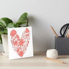 a heart shaped card with flowers and leaves on it art board print by the paper quill