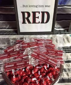 a bowl filled with red candy sitting on top of a table next to a sign