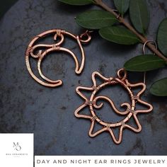 a pair of earrings made out of copper wire sitting on top of a stone slab