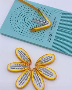 two pieces of yellow and silver thread on top of a blue board