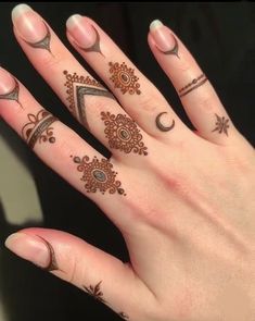 a woman's hand with henna tattoos and rings on her fingers, showing the design