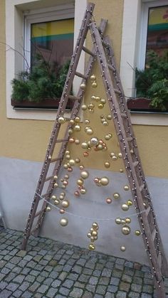 a ladder decorated with christmas balls on the side of a building