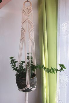 a macrame plant hanging from the side of a wall next to a window