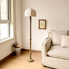 a white couch sitting next to a lamp on top of a hard wood floor in a living room