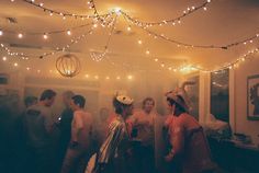 a group of people standing around each other in a room with lights on the ceiling